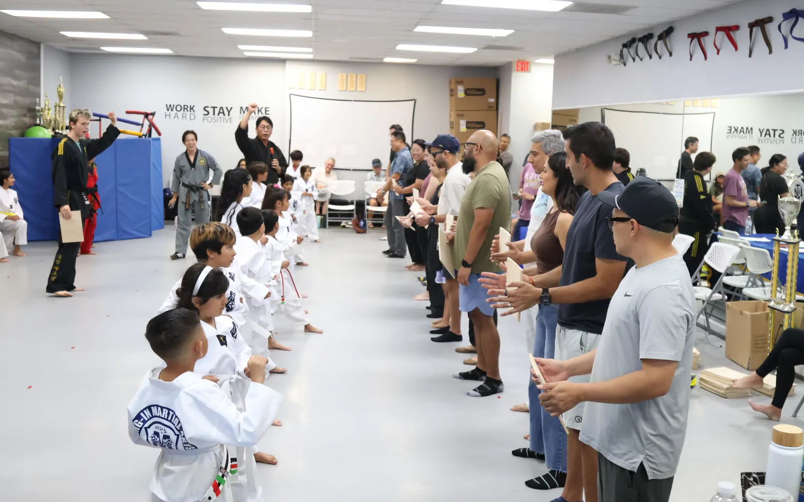 Belt ceremony with families watching along the mat