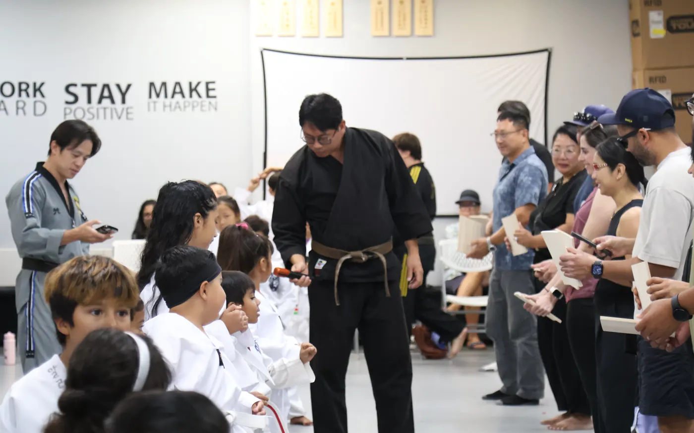 Instructor handing out certificates to students with parents watching