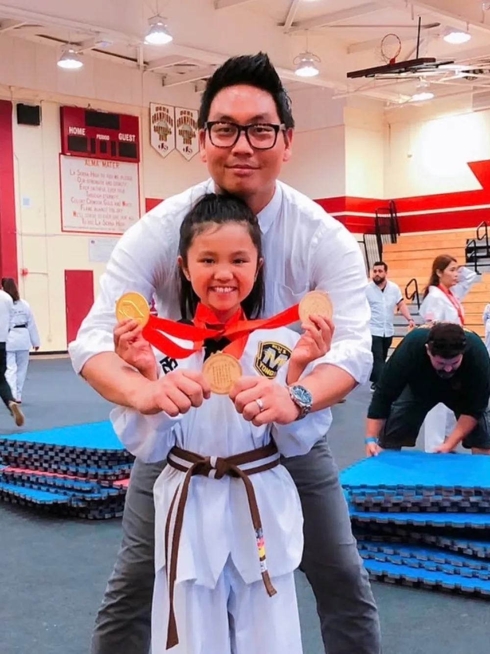 Instructor with a student showing her medals after a tournament