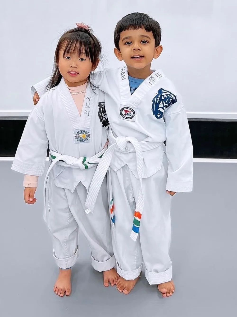 Two preschool-age students in uniform, arm around each other