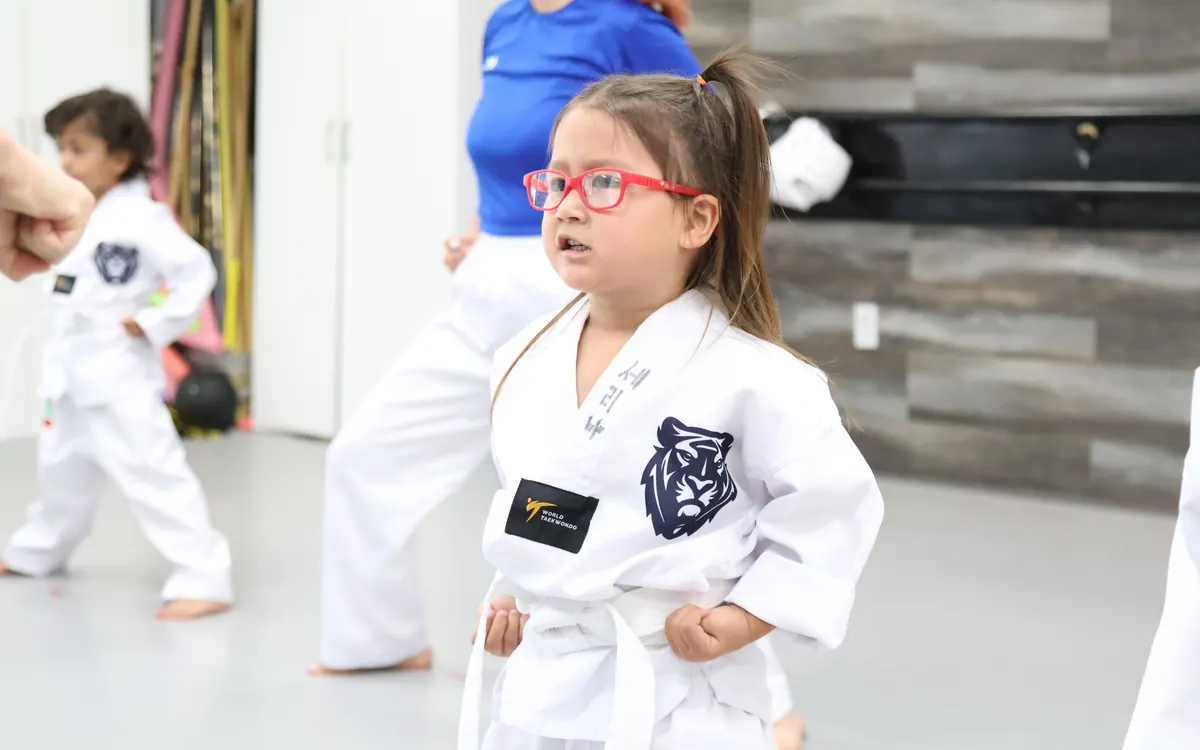 Preschool-age children in white uniforms in a Little Tigers class