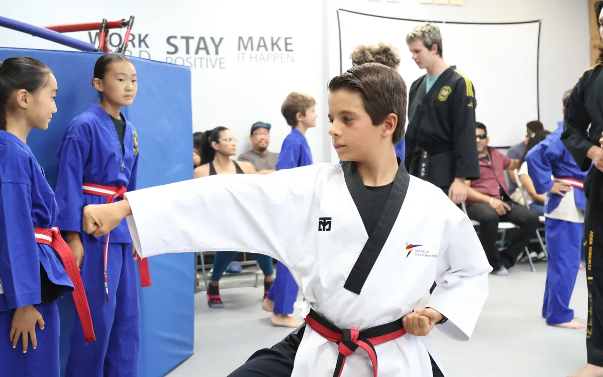 Teen student in a black uniform demonstrating technique